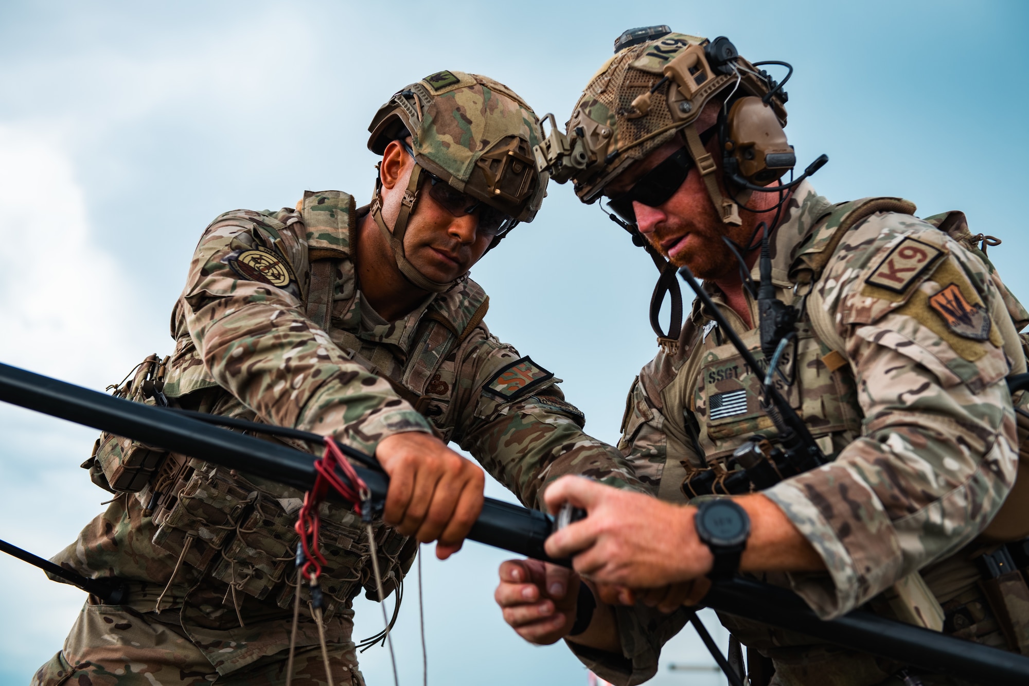 Airmen tape a cable to an antenna.