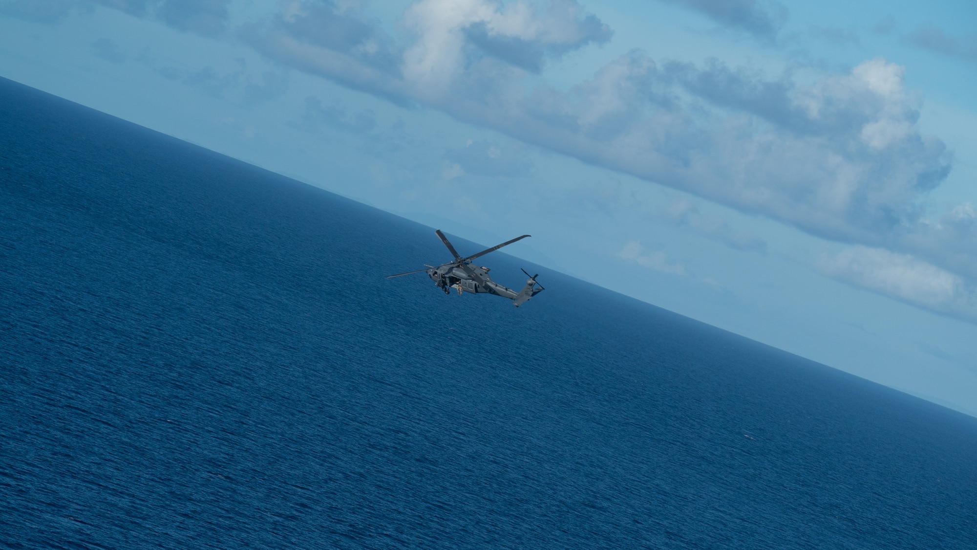 An HH-60W flys over the Pacific Ocean.