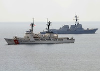 The Arleigh Burke-class guided-missile destroyer USS Chung-Hoon and U.S. Coast Guard cutter Mellon pass each other during a surface gunfire exercise.