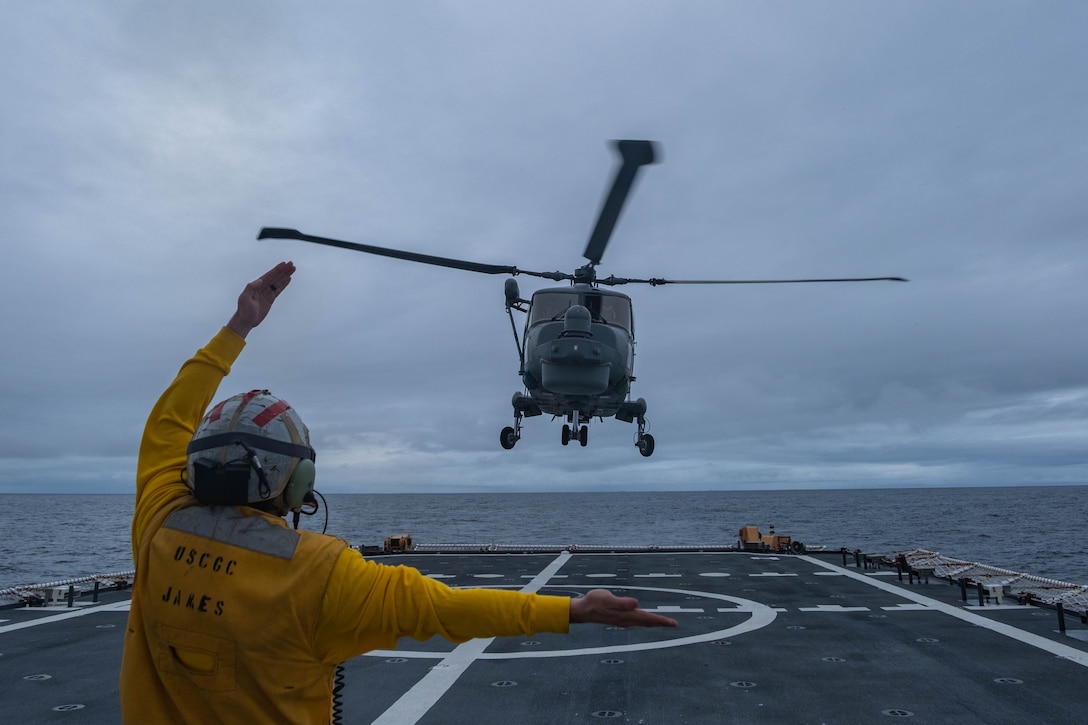 U.S. Coast Guard Petty Officer 1st Class Tyler Deitrick signals a Brazilian navy Westland Super Lynx Mk-21A crew to land onboard the U.S. Coast Guard Cutter James (WMSL 754) while at sea in the Southern Atlantic Ocean May 15, 2024. Deitrick signaled the helicopter to take off to the port side of James as part of a training exercise. (U.S. Coast Guard photo by Petty Officer 3rd Class Logan Kaczmarek)