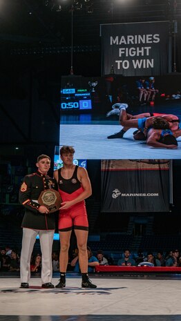 U.S. Marine Corps Staff Sgt. Mark Berry, a water safety survival instructor with The Basic School, Marine Corps Base Quantico, presents a first-place award (16U) to Carter Temple, the National Champion, at the 2024 U.S. Marine Corps Junior & 16U Nationals in Fargo, North Dakota, July 20, 2024. The Marine Corps’ partnership with USA Wrestling started in 2017 as a way for Marines to develop new relationships with wrestling coaches. These partnerships ensure the coaches of the next generation of Marines are aware of Marine Corps opportunities, provide advocacy and support recruiter access to prospective audiences, which is critical to our nation's defense. (U.S. Marine Corps photo by Sgt. Jesse K. Carter-Powell)