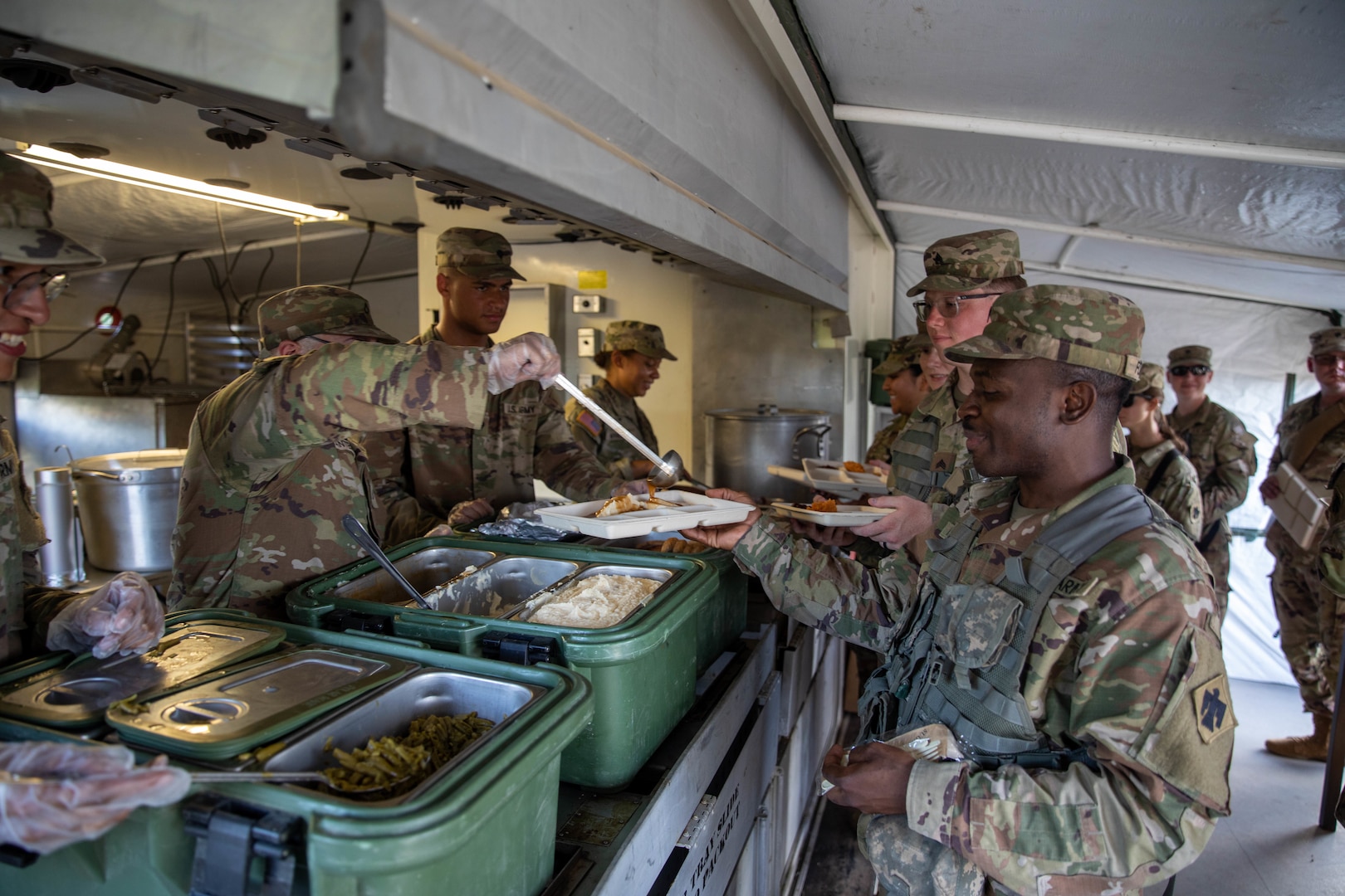 Soldiers from the Oklahoma Army National Guard’s 700th Brigade Support Battalion, 45th Infantry Brigade Combat Team, get food from the mobile kitchen trailer at the brigade support area at Glenwood Training Area in Midwest City, Oklahoma, July 13, 2024. The 700th BSB manages and supplies all the 45th Infantry Brigade Combat Team’s maneuver battalions and their forward support companies with all of their commodities, including food, water, fuel, ammunition, parts, and maintenance. (Oklahoma National Guard photo by Sgt. Haden Tolbert)