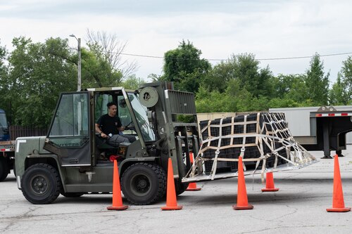 Walsh drives a forklift between orange traffic cones while carrying a pallet.