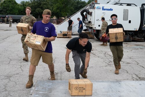 Four Airmen rush to load boxes into a pallet.