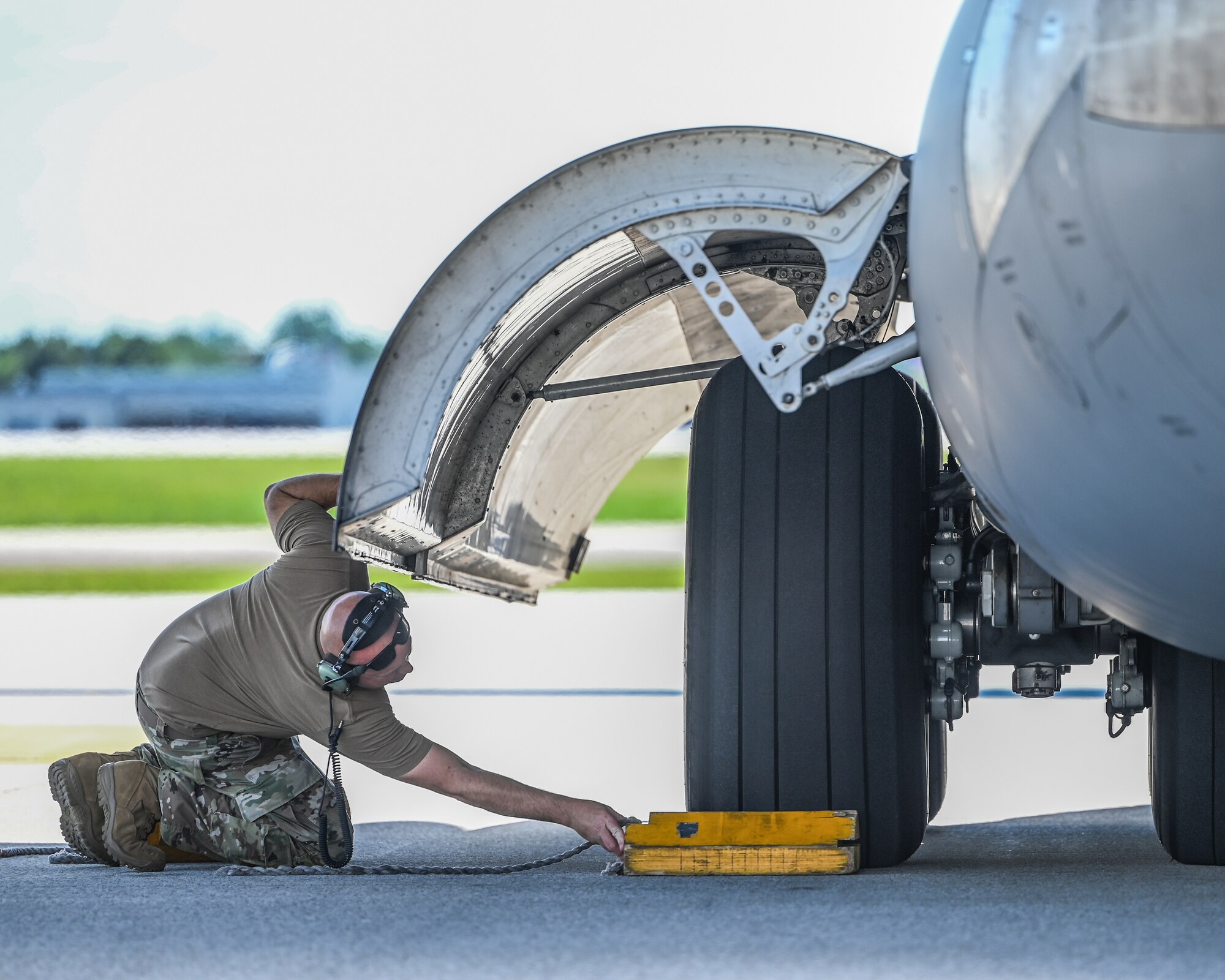 Master Sgt. Spencer Fisher, 445th Aircraft Maintenance Squadron crew chief, places a chock under the wheel of a C-17 Globemaster III after a flight at Wright-Patterson Air Force Base, Ohio, July 16, 2024.Crew chiefs conduct a variety of tasks after an aircraft completes a flying mission.