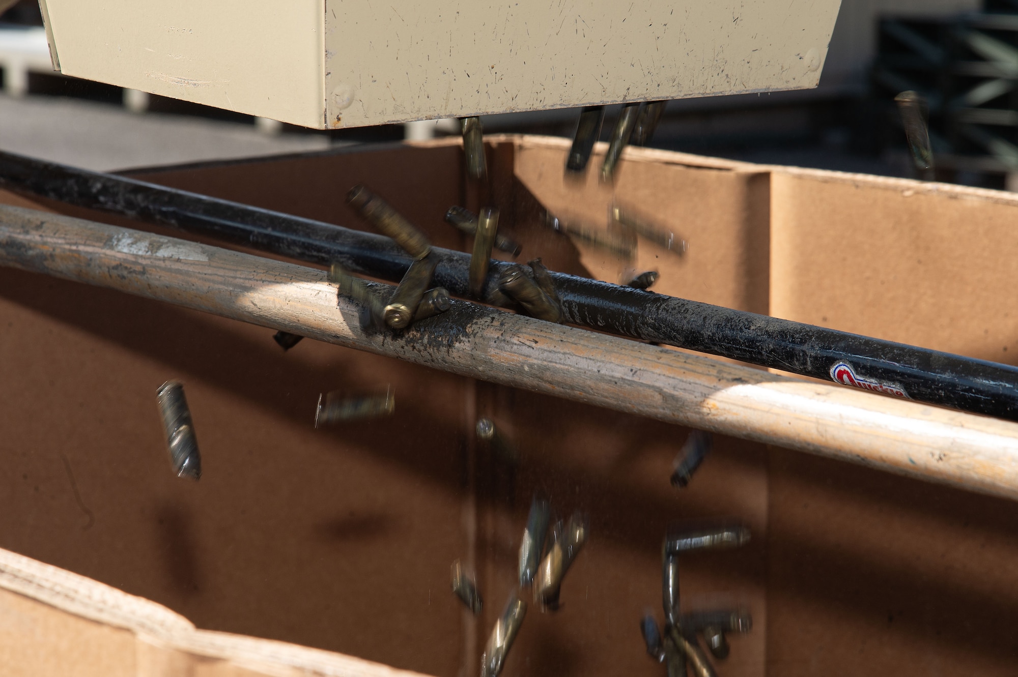 Demilitarized small caliber brass munition cartridges fall from the deformer into a Triple-Wall cardboard box at Dover Air Force Base, Delaware, May 1, 2024. From its first use in February 2019, proceeds from brass sales have paid for the deformer and are now generating revenue for the base. (U.S. Air Force photo by Roland Balik)