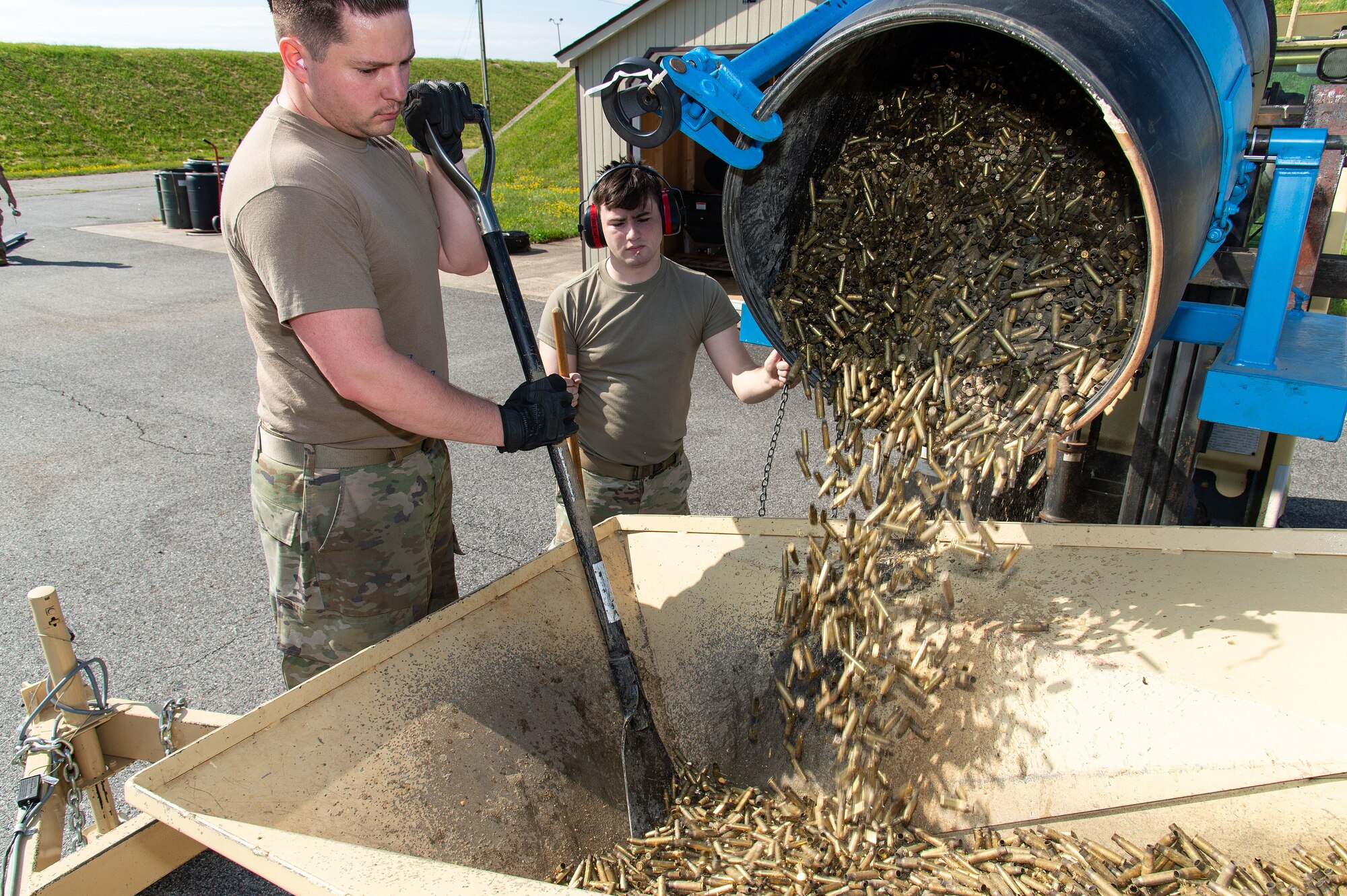 U.S. Air Force Senior Airmen Nathaniel Weikert, left, and Brian Rice, right, 436th Maintenance Squadron munitions crew chiefs, load small caliber brass munition cartridges into a deformer to be demilitarized at Dover Air Force Base, Delaware, May 1, 2024. From its first use in February 2019, proceeds from brass sales have paid for the deformer and are now generating revenue for the base. (U.S. Air Force photo by Roland Balik)