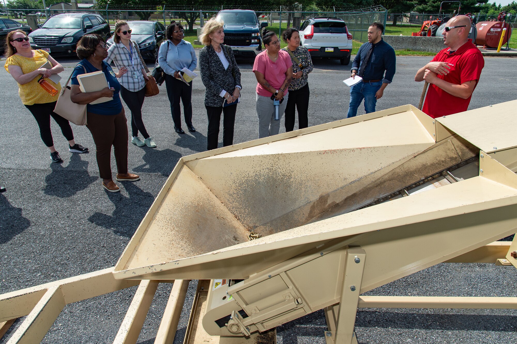 Ken Riley, right, 436th Civil Engineer Squadron Qualified Recycling Program manager, answers questions from Air Force Civil Engineer Center and regional solid waste and recycling managers about the brass deformer process and operation at Dover Air Force Base, Delaware, May 8, 2024. The deformer demilitarized small caliber brass munition cartridges. (U.S. Air Force photo by Roland Balik)