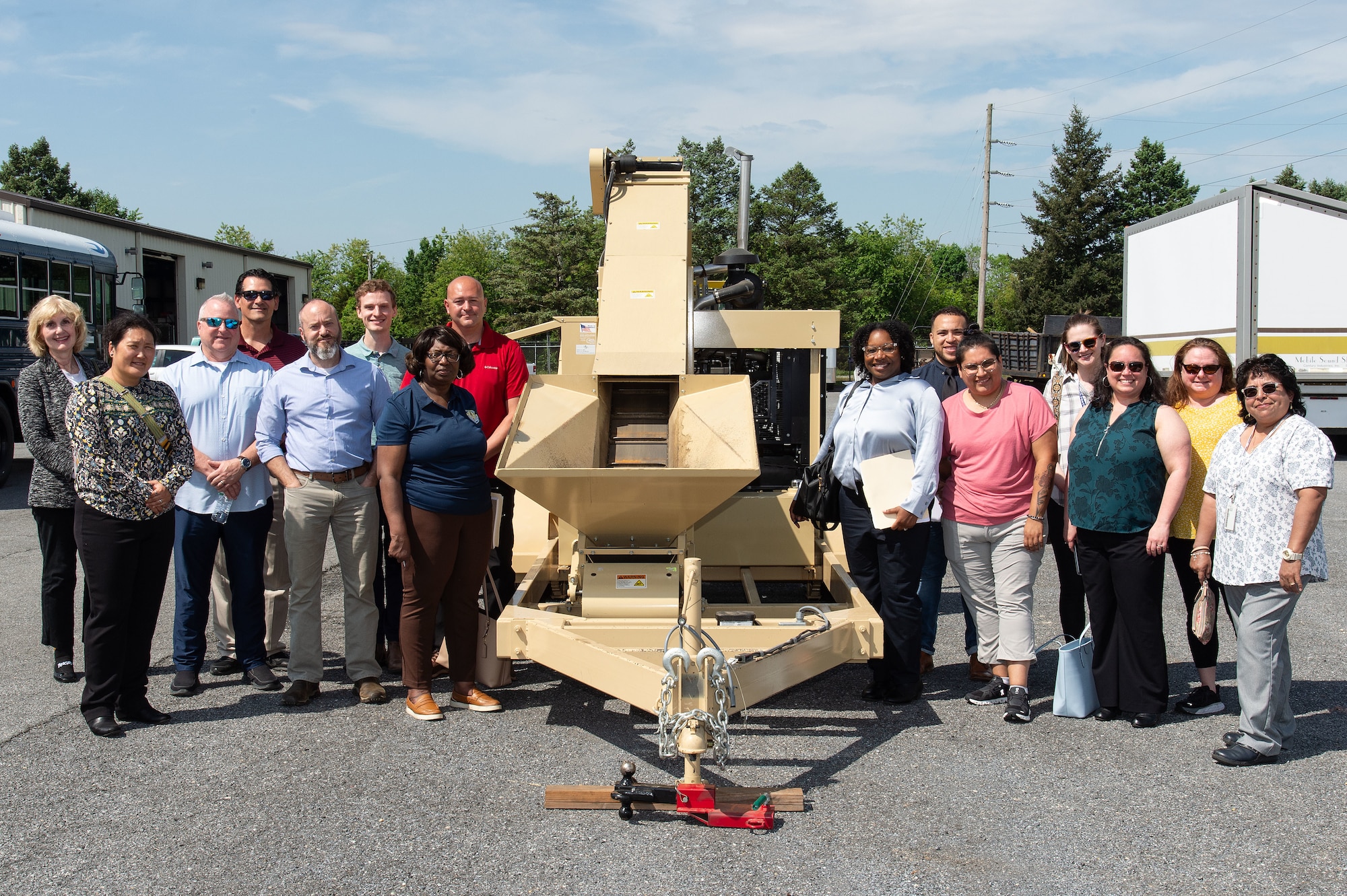 Individuals from the 436th Civil Engineer Squadron, Air Force Civil Engineer Center and regional solid waste and recycling managers pose for a photo by a brass deformer at Dover Air Force Base, Delaware, May 8, 2024. The 436th CES hosted the Integrated Solid Waste Program Management Review attended by regional Qualified Recycling Program managers. (U.S. Air Force photo by Roland Balik)