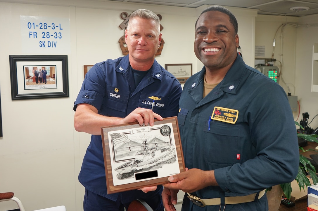 Coast Guard Capt. Jonathan Carter, left, commanding officer of Coast Guard Cutter Stone (WMSL 758), presents Navy Cmdr. Roosevelt White, commanding officer of Arleigh Burke-class guided-missile destroyer USS Donald Cook (DDG 75) with an engraved plaque, June 24, 2024, while underway in the Atlantic Ocean aboard Stone. The units are operating in the Atlantic Ocean in support of maritime stability and security in the region. (U.S. Coast Guard photo by Ensign Alana Kickhoefer)