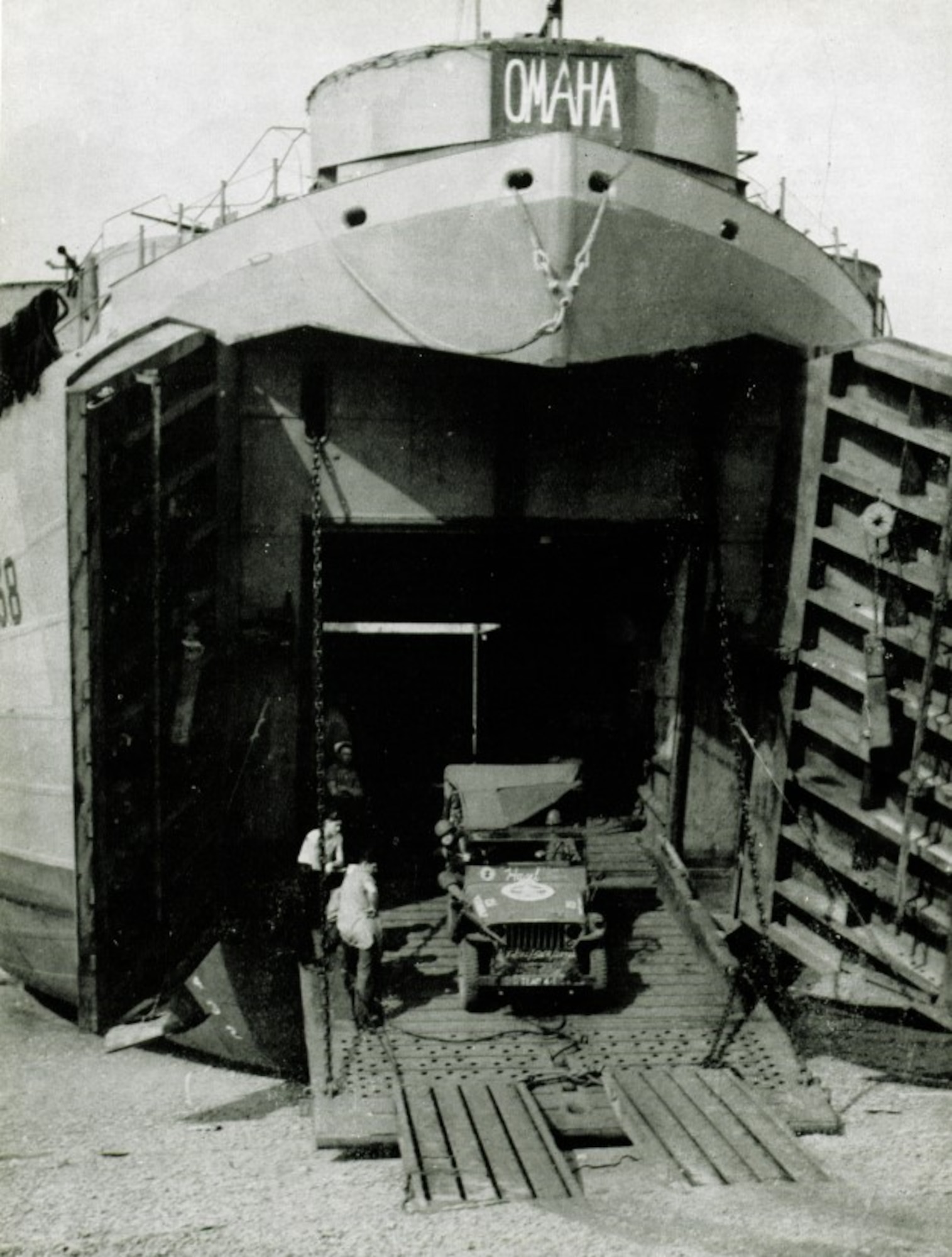 U.S. Navy tank landing ship LST-138 seen here disgorging a jeep was likely one of the several LSTs which brought various echelons of the 371st Fighter Group to France. The big OMAHA placard indicates a vessel destined for Omaha Beach, where elements of the group’s rear echelon landed on July 7/8 1944, completing the movement of the group across the English Channel from Great Britain to France and ALG A-6. (The Story of the 371st Fighter Group in the E.T.O.)