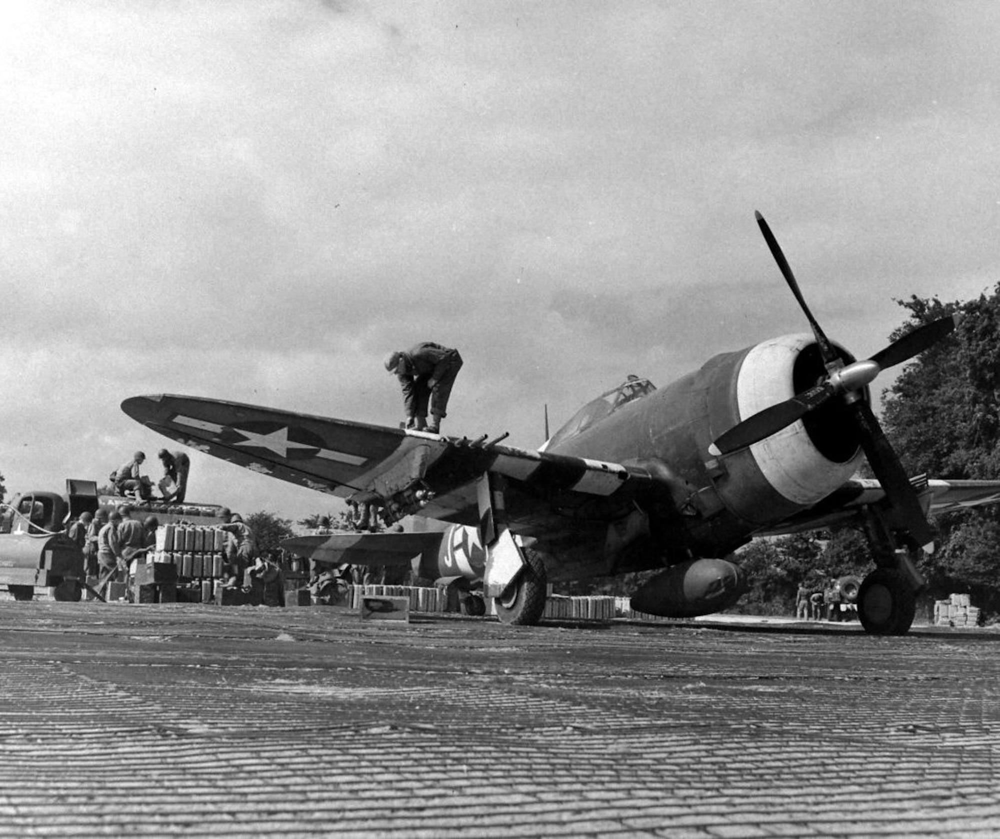 An undated picture taken at ALG A-6 in the summer of 1944 shows a P-47D Thunderbolt of an unidentified unit undergoing rearming and refueling. This was likely taken in the early days of the airfield’s operations in mid-June, 1944. Note the fragmentation bombs beneath the wings, and the soldiers filling a refueling bowser from jerrycans which were likely flown in to A-6 on C-47 transport aircraft during the early days of A-6 operations. (US Army photo via Flickr)