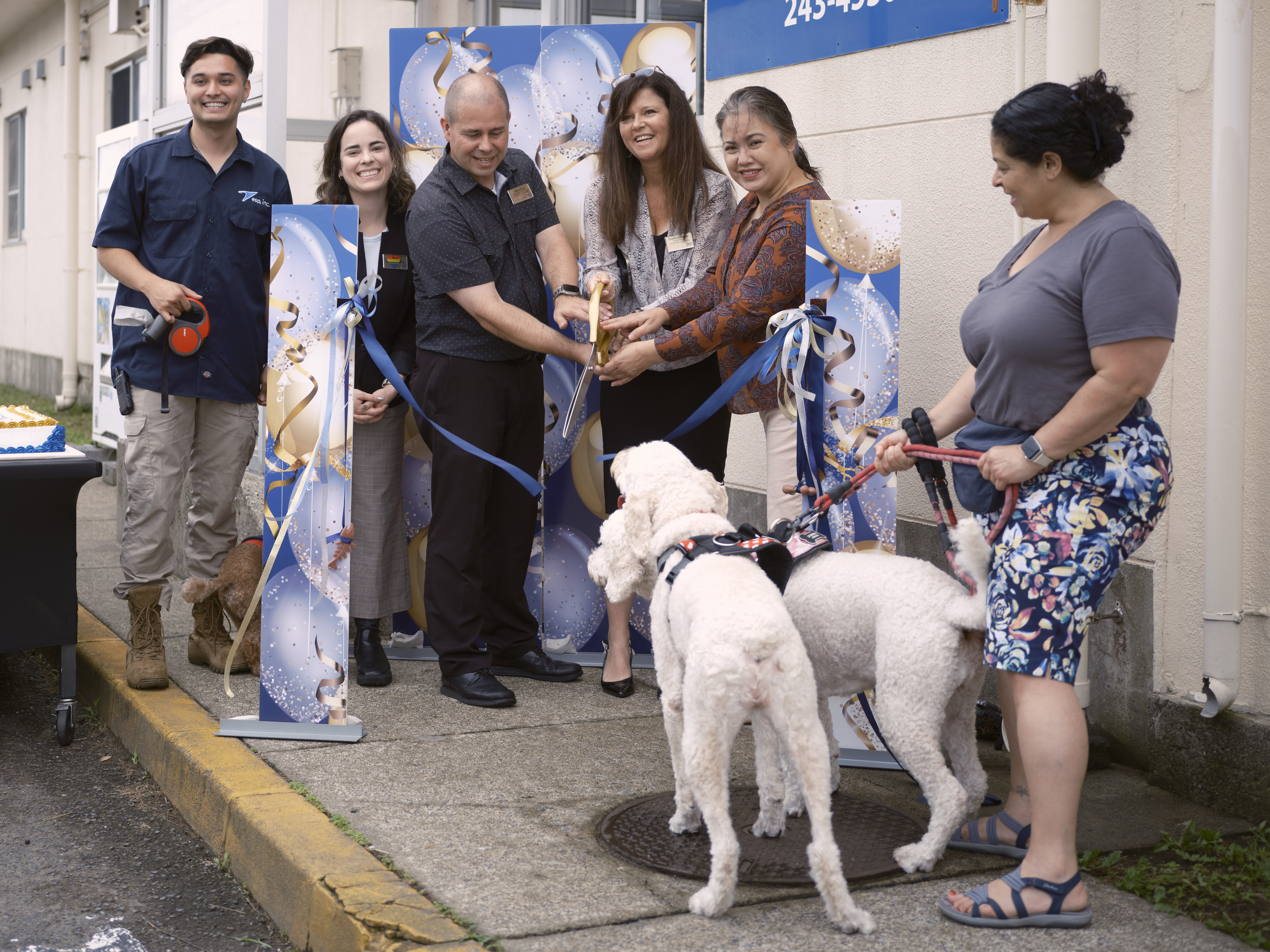 Navy Exchange Yokosuka General Manager Charlene DuBose (center), Navy Exchange Yokosuka Services Operations Manager Jimmy Green (left), Annie Sobol (right) and other base community members cut the ceremonial ribbon outside the NEX Kennel during the Grand Re-Opening Paw-ty July 17, 2024 on Commander, Fleet Activities Yokosuka's Main Base.
