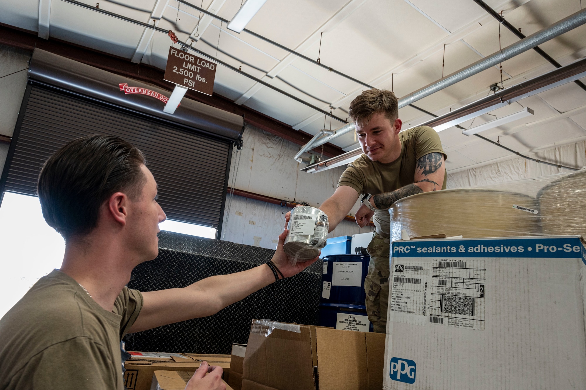 U.S. Air Force Airman Logan Dombrowski, 49th Logistics Readiness Squadron HAZMART journeyman, left, and U.S. Air Force Senior Airman Christian Goodwin, 49th LRS HAZMART journeyman, unload a coating kit for rain erosion at Holloman Air Force Base, New Mexico, July 18, 2024. The HAZMART section is responsible for shipping and storing a wide range of hazardous materials, ensuring safe delivery to multiple organizations across the base. (U.S. Air Force photo by Senior Airman Isaiah Pedrazzini)