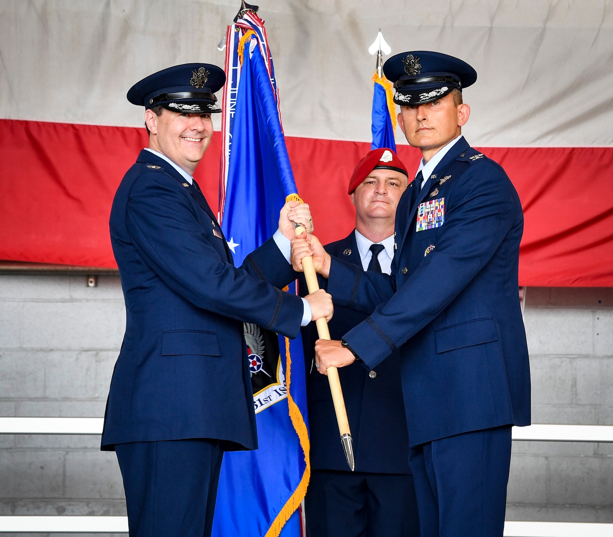 Two Air Force members hold a flag on a stage.