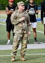 Man in Army uniform standing on football field speaking