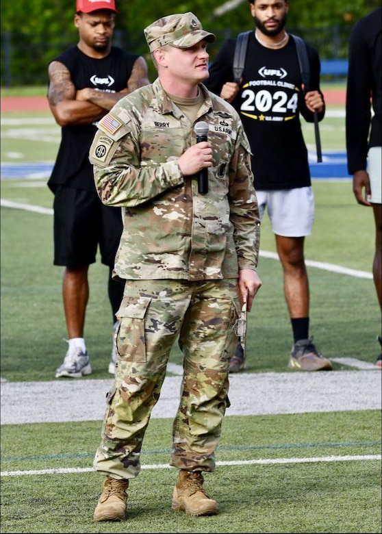 Man in Army uniform standing on football field speaking