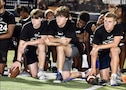 Local high school football players pause at a football clinic for a block of instruction.