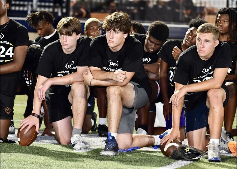 Local high school football players pause at a football clinic for a block of instruction.