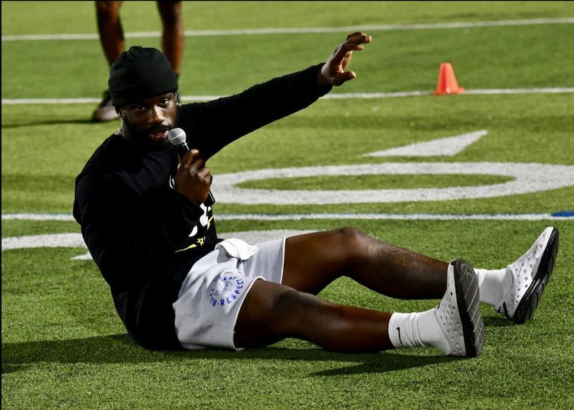 Man on football field speaks into microphone.