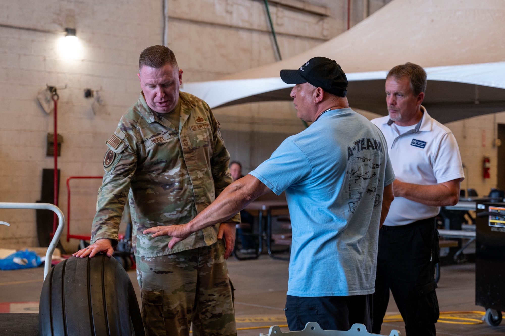 Javier Martinez, 97th Maintenance Squadron configurations work leader, presents a KC-46 Pegasus aircraft tire to Chief Master Sgt. Chad Bickley, command chief of Air Education and Training Command, at Altus Air Force Base, Oklahoma, July 11, 2024. Martinez explained the recently developed refurbishment process for KC-46 tires. (U.S. Air Force photo by Airman 1st Class Heidi Bucins)