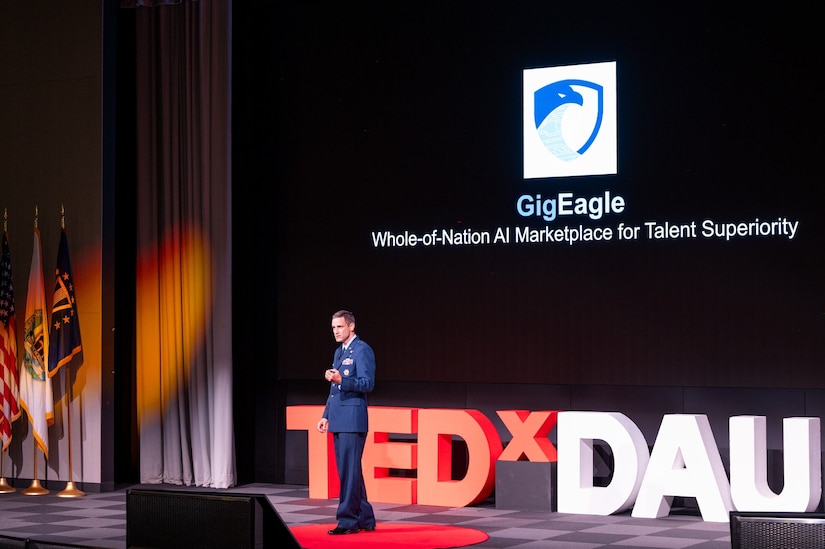 A service member in uniform stands on a stage.