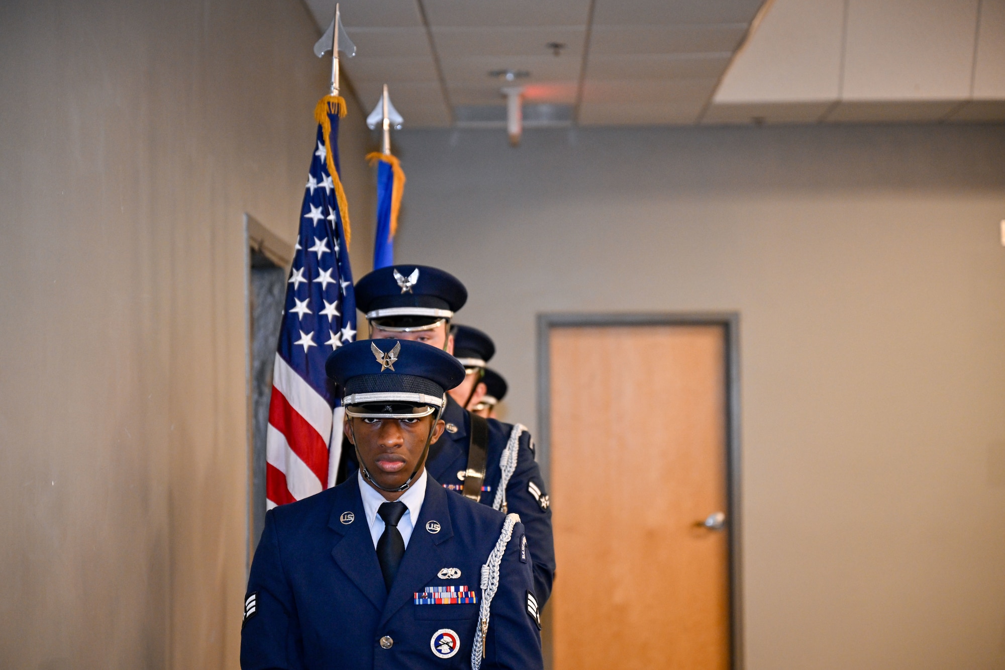 Men in uniform stand holding flags at a ceremony.