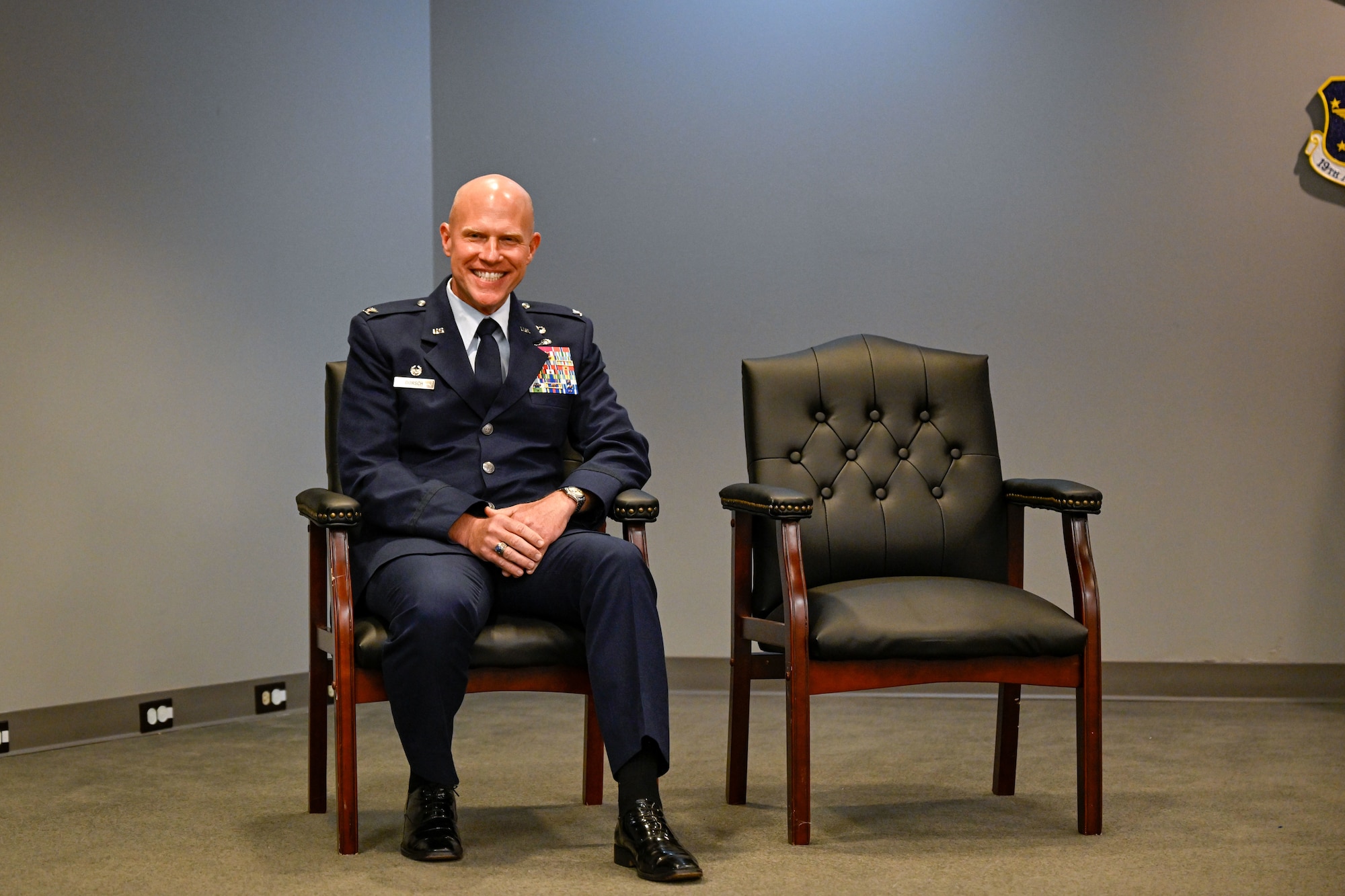 A man in uniform sits in a chair at a ceremony.