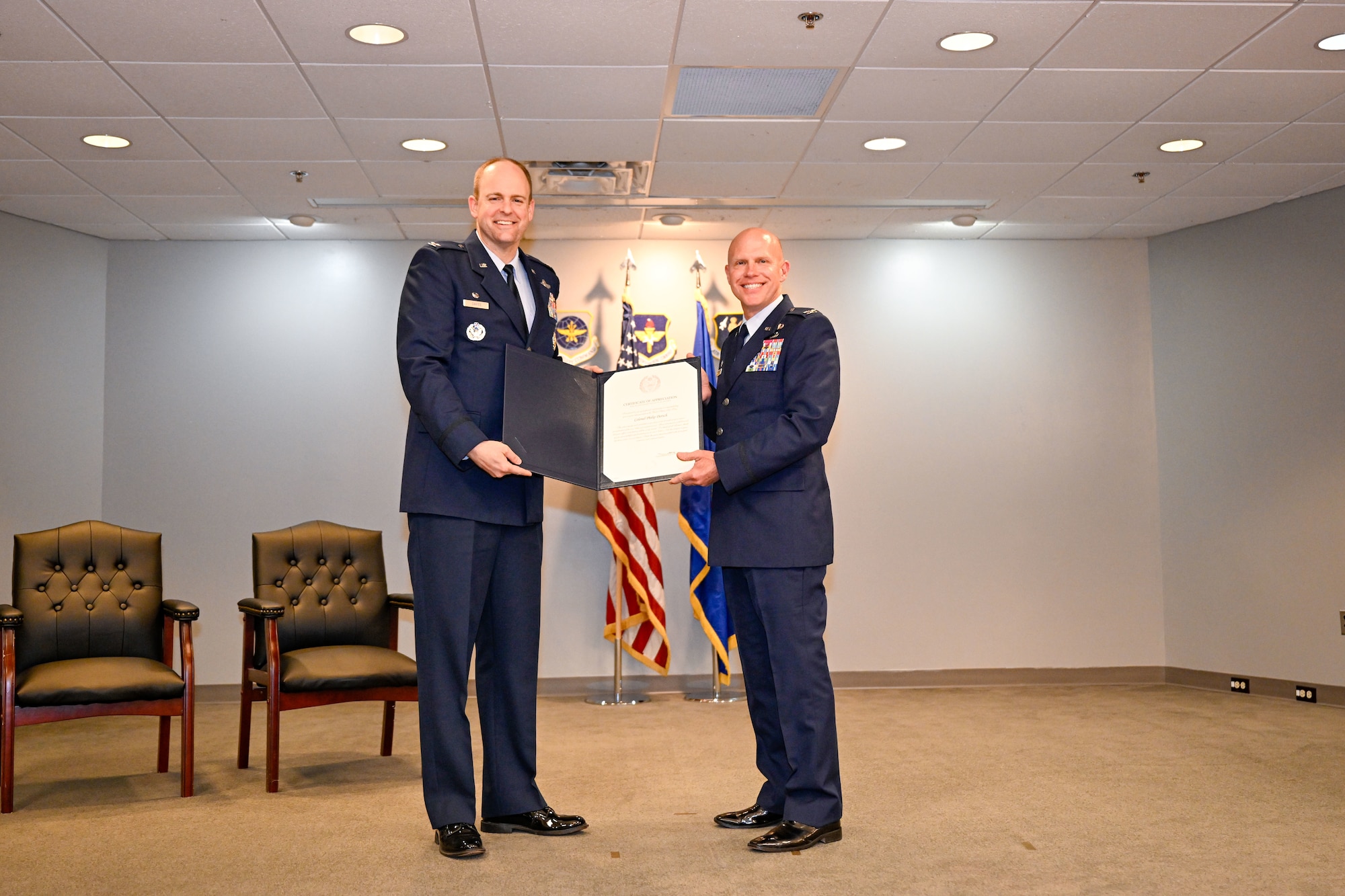 Two men holding a booklet containing a certificate.