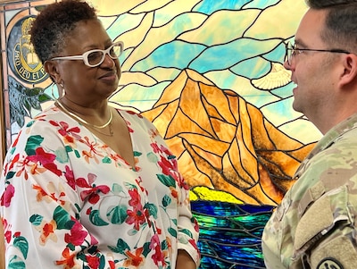 Woman speaking to the hospital Chaplain in front of a stained-glass window.