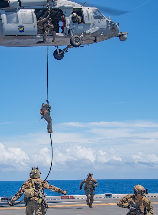 Marines from the 31st Marine Expeditionary Unit fast-rope from a Helicopter Sea Combat Squadron (HSC) 25 MH-60S Seahawk to the flight deck of the forward-deployed amphibious assault ship USS America (LHA 6) during a visit, board, search and seizure (VBSS) exercise while conducting routine operations in the Philippine Sea, July 25.
