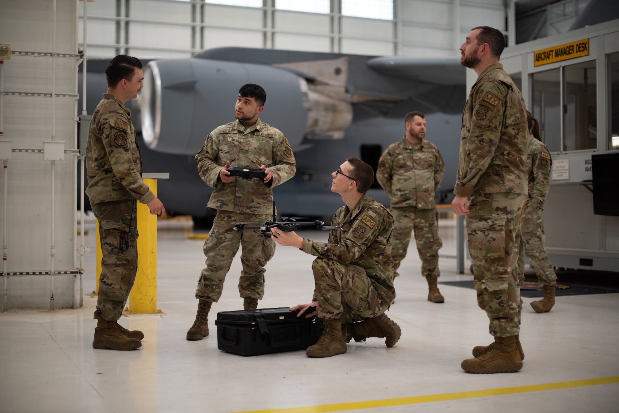 Airmen discuss drone operation while one airman holds the drone