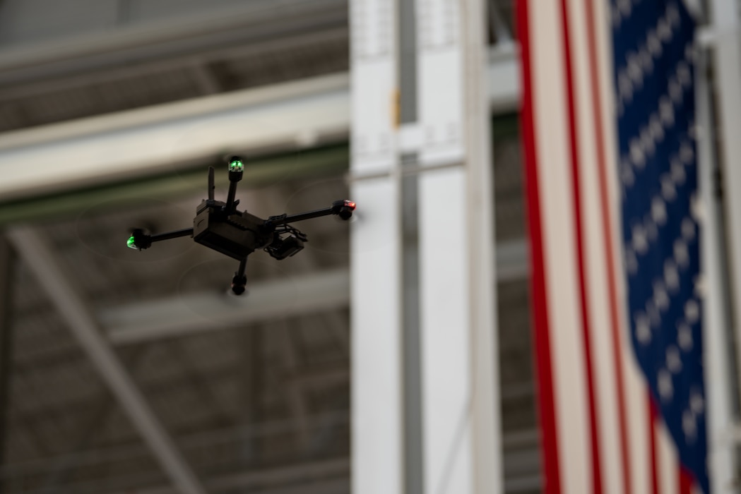 A drone flies by a large American flag