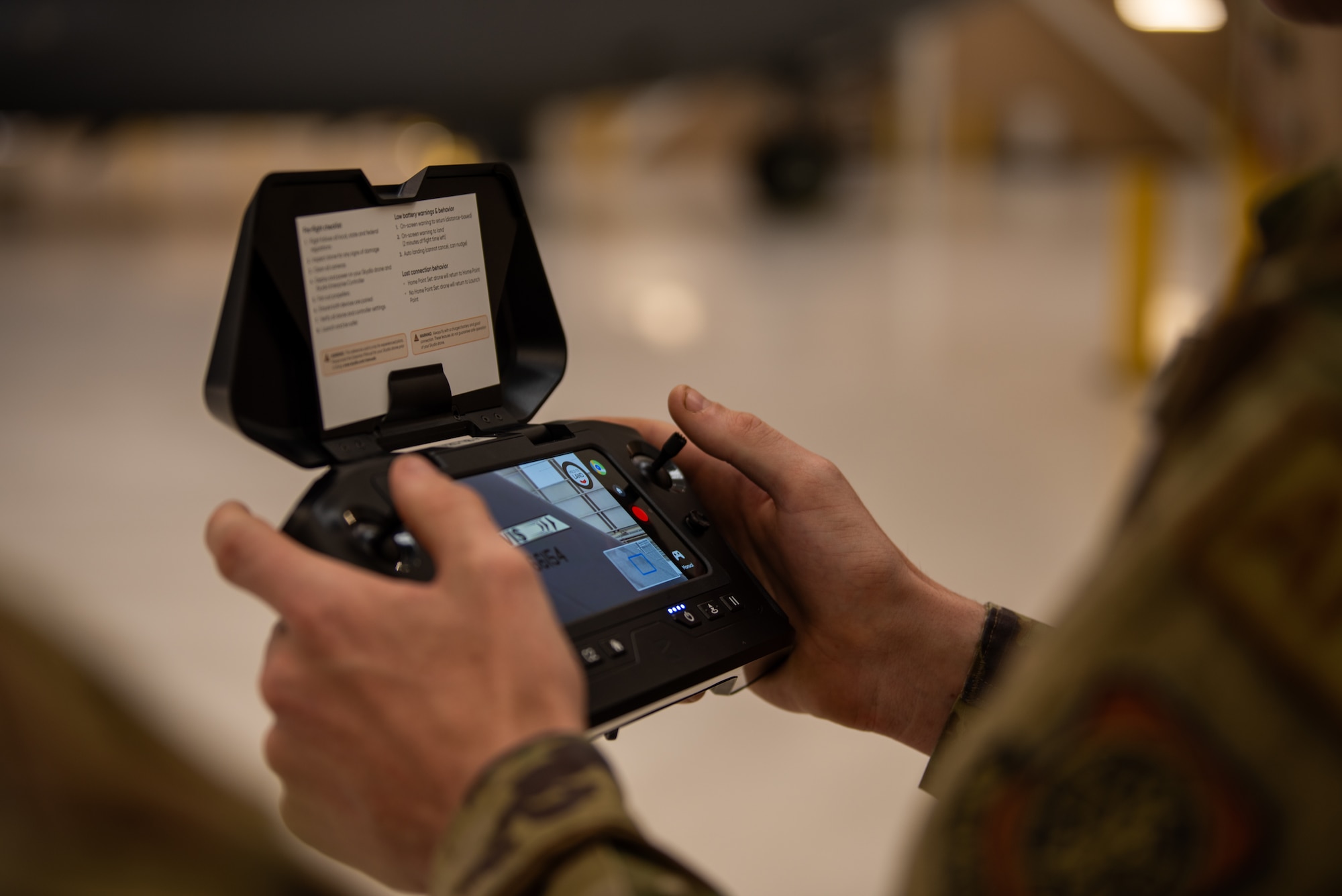 A drone controller is being operated in the hands of an airman