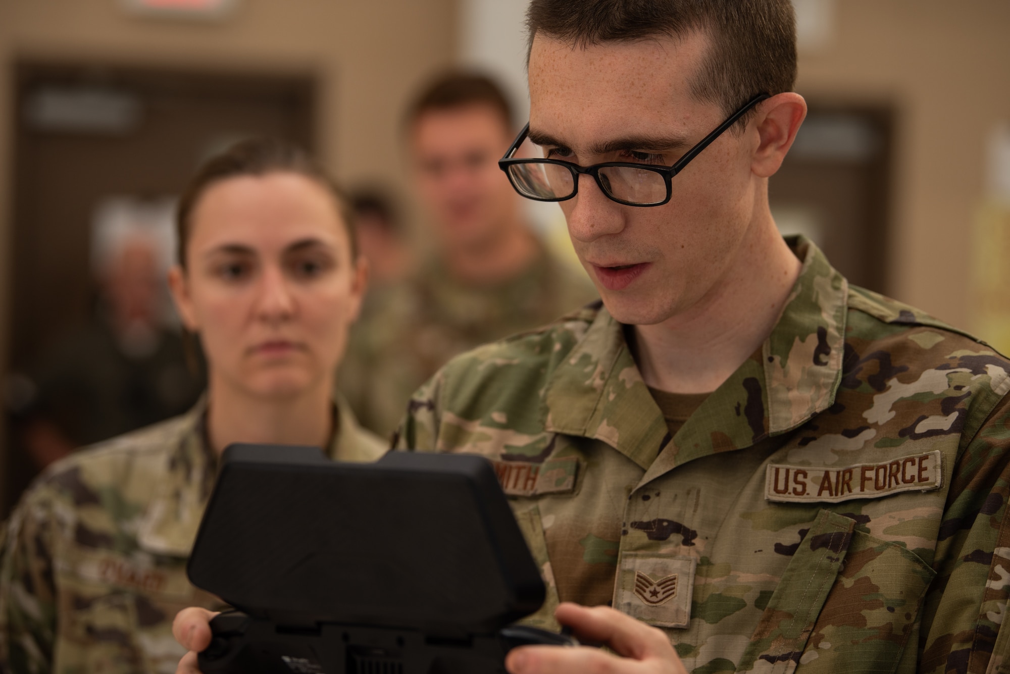 An airman operates a drone controller