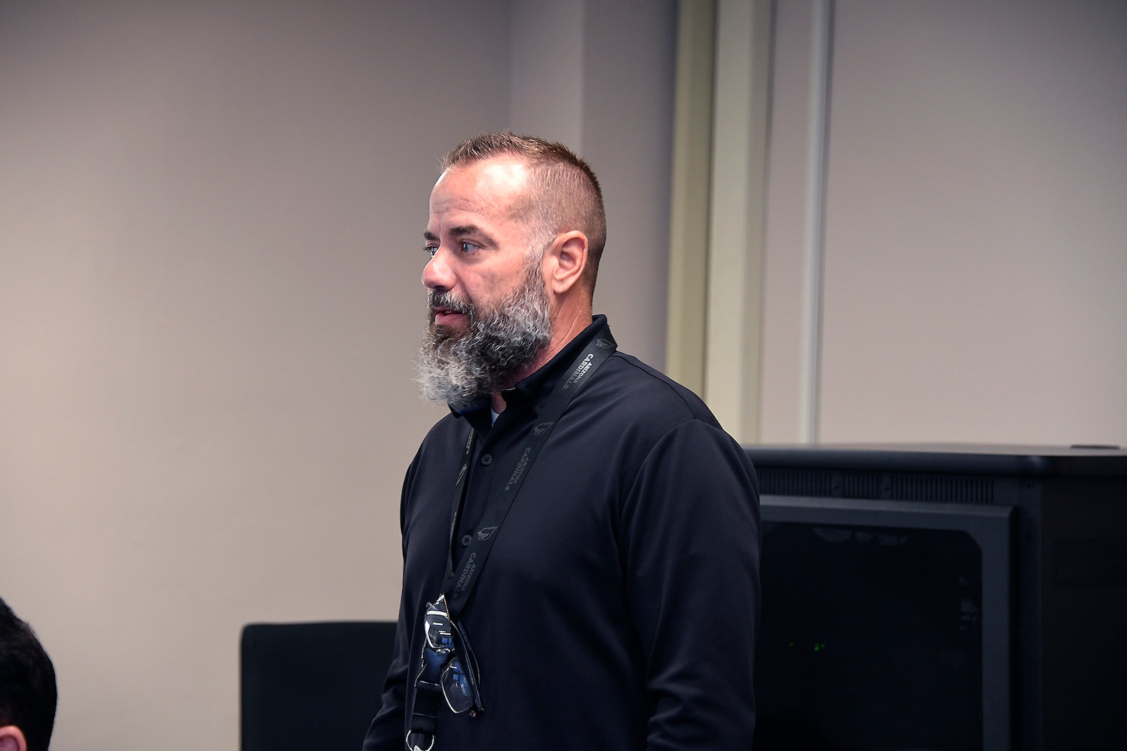 Side profile of a white man with a beard in a black shirt