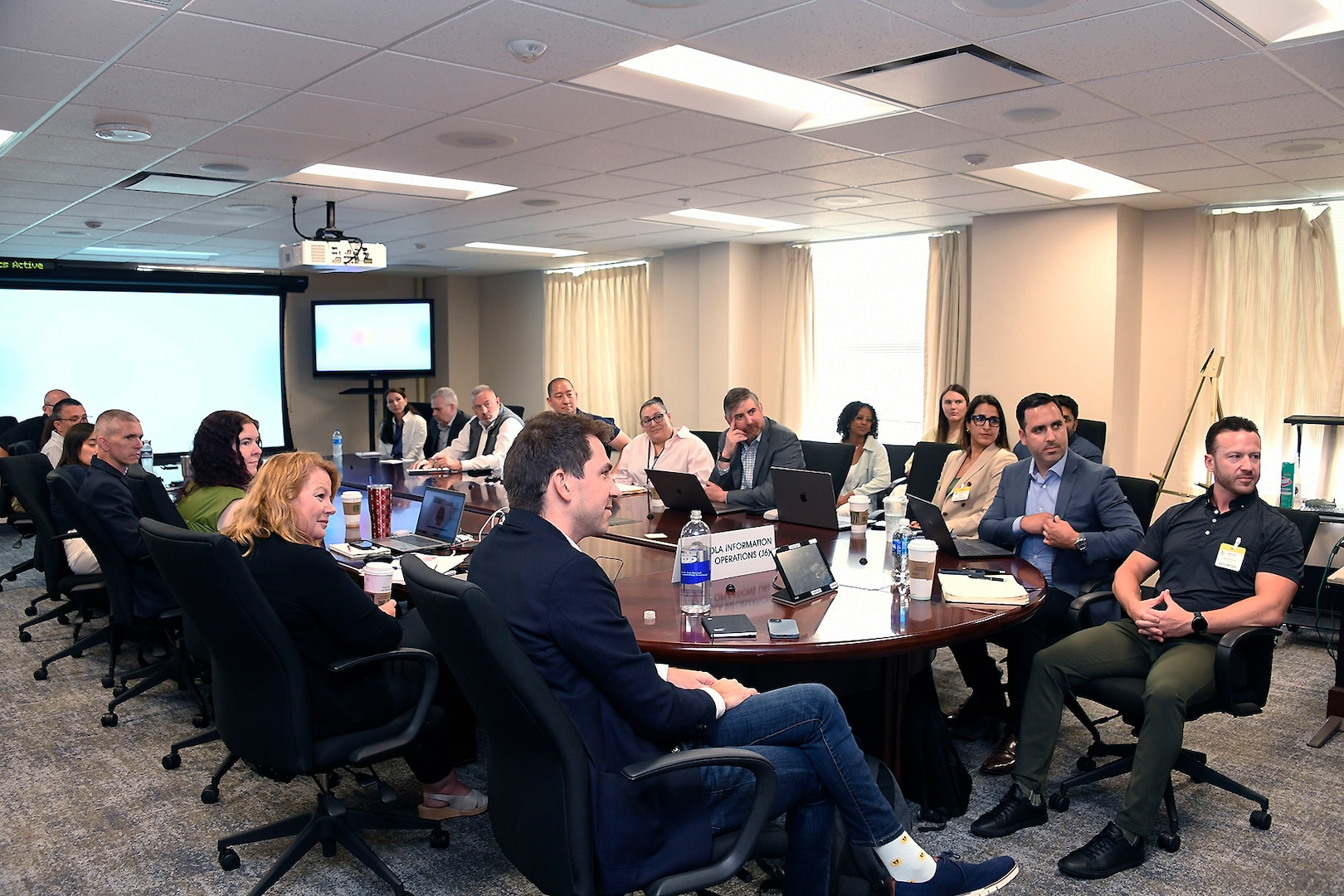 About 20 people sit around a rectangular table