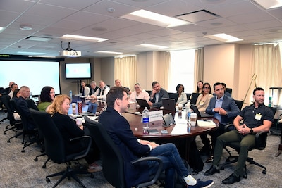 About 20 people sit around a rectangular table