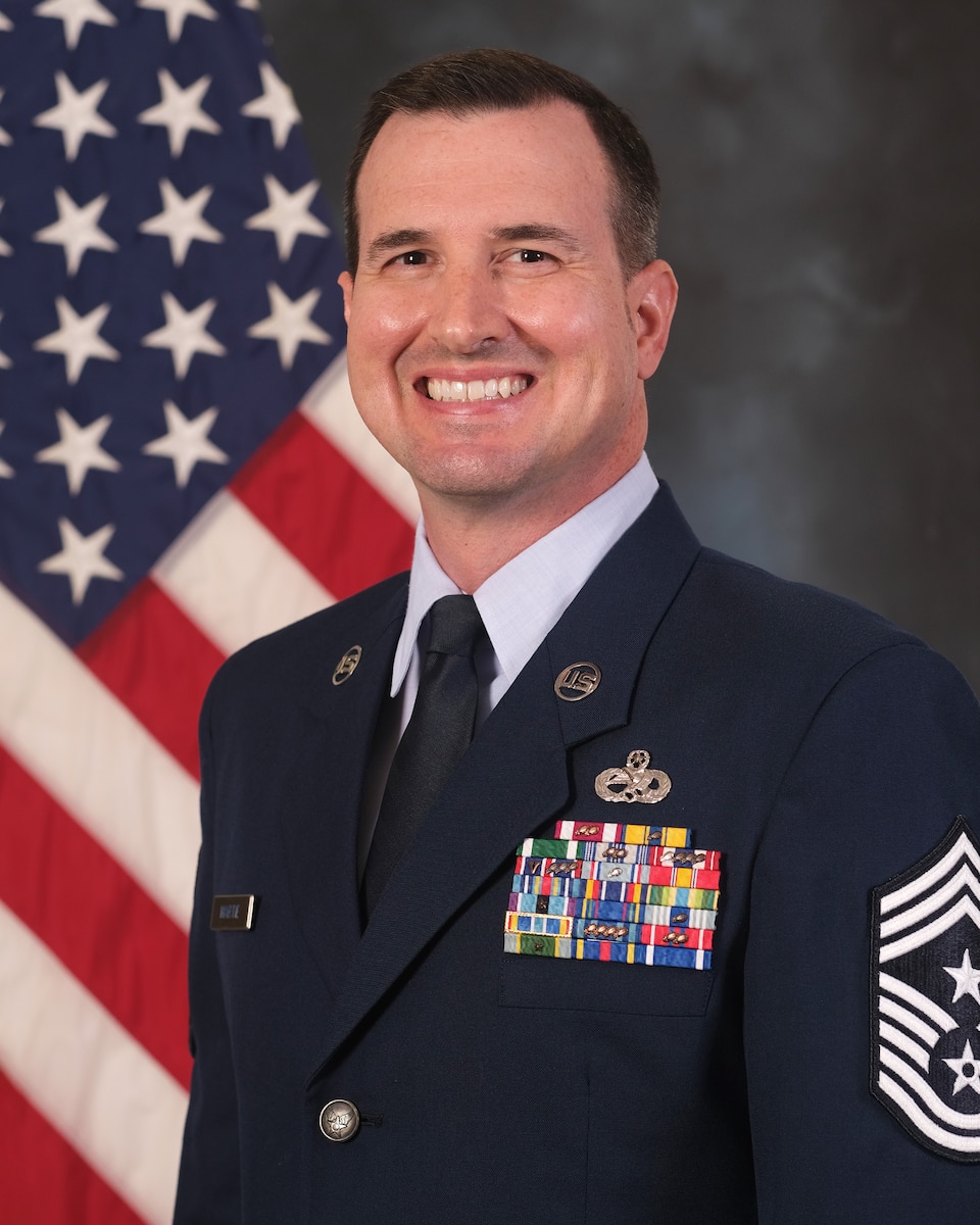 photo of U.S. Air Force Airman standing in front of U.S. flag and gray background