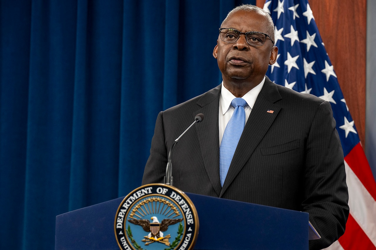 Secretary of Defense Lloyd J. Austin III stands and speaks on a podium with the American flag behind him.