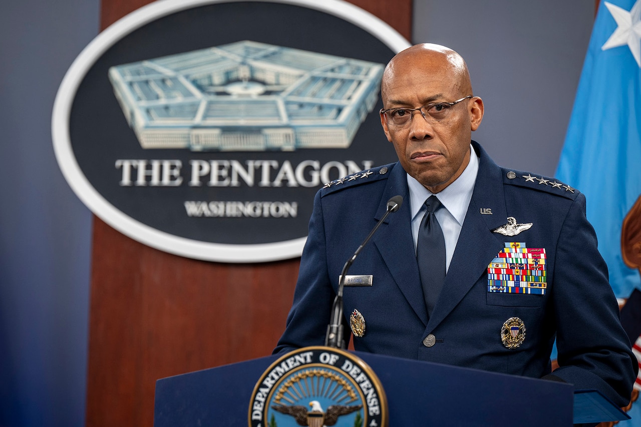 A general stands on a podium with a microphone with the Pentagon logo behind him.