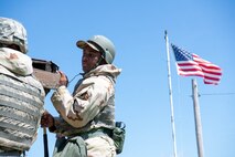 An Airman stands on a ladder fixing a building