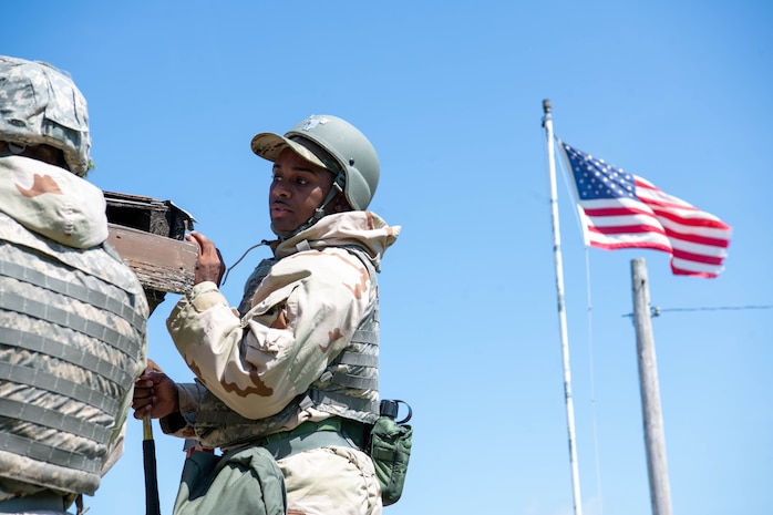 An Airman stands on a ladder fixing a building