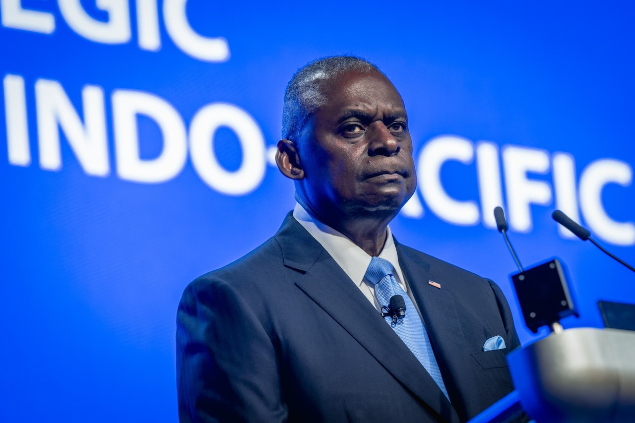 A man in civilian attire stands at a lectern.