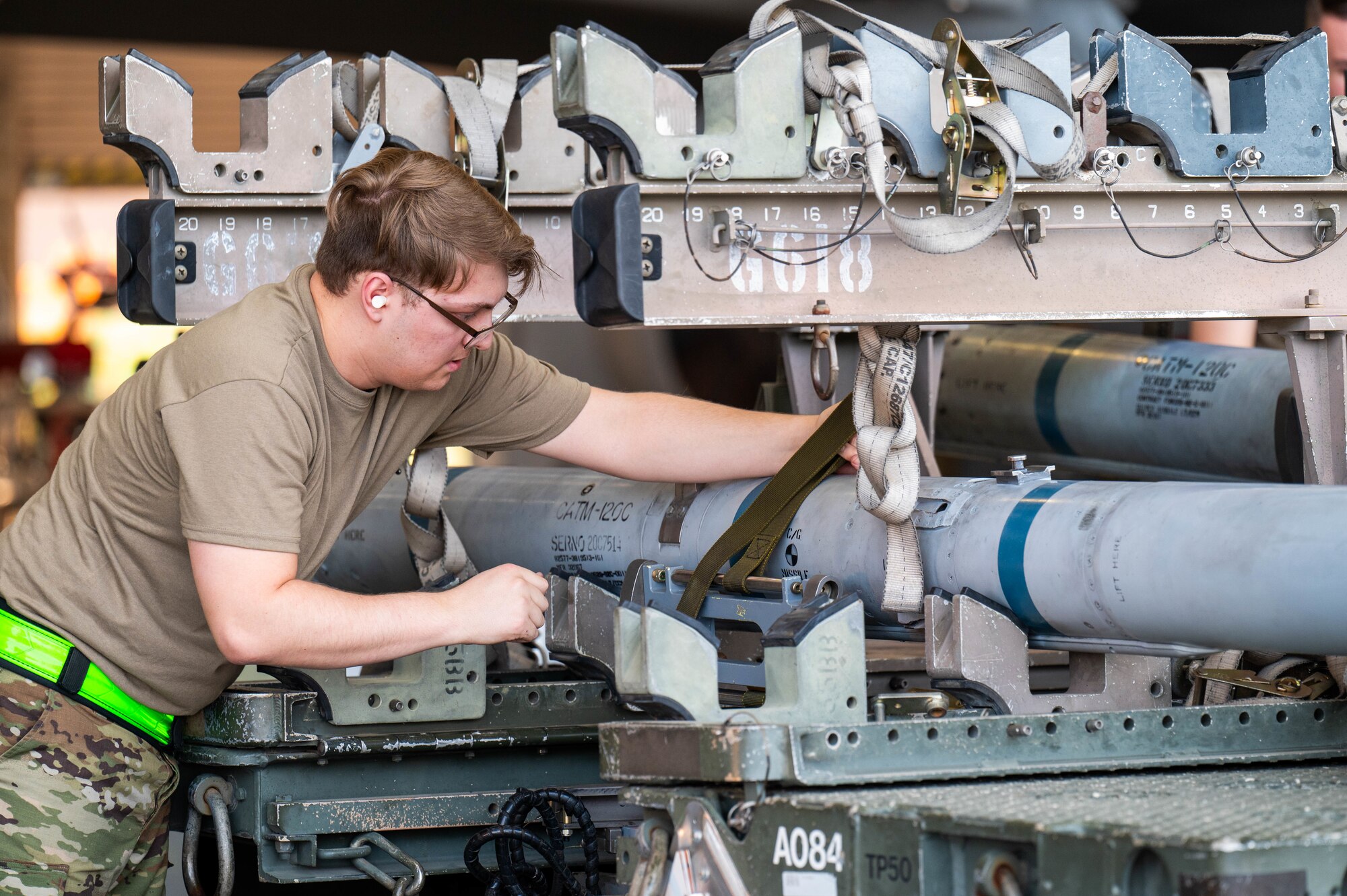 U.S. Air Force Staff Sgt. Tyler Rosado, 310th Aircraft Maintenance Unit maintainer, unstraps an AIM-120 AMRAAM missile during the 56th Maintenance Group 2nd quarter weapons load competition, July 12, 2024, at Luke Air Force Base, Arizona.