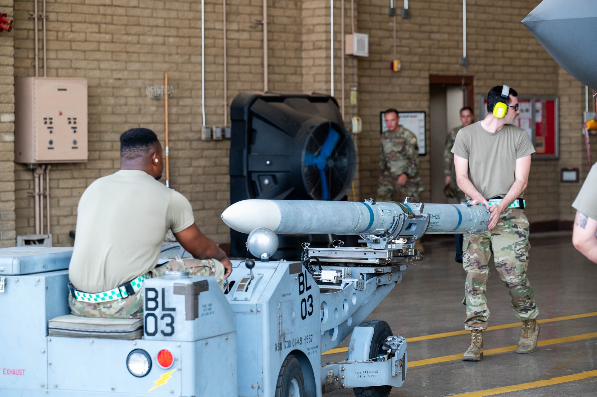U.S. Air Force Senior Airman Nicholas Reynolds (right) and Senior Airman Jaire Whitehead (left), 310th Aircraft Maintenance Unit maintainers, guide an AIM-120 AMRAAM missile during the 56th Maintenance Group 2nd quarter weapons load competition, July 12, 2024, at Luke Air Force Base, Arizona.