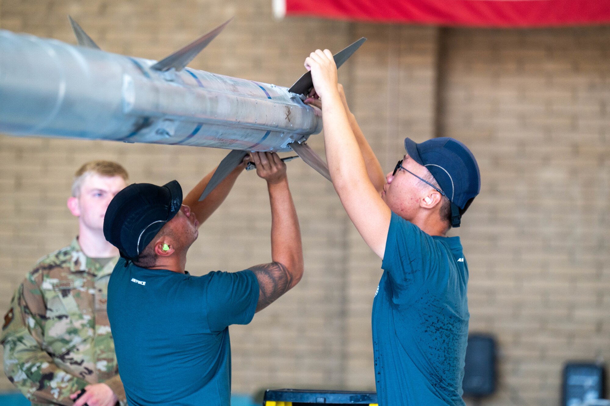 Republic of Singapore air force ME2 Jeff Hong (left), and ME1 Wei Shen Tang (right), load stabilizing fins to an AIM-120 AMRAAM missile during the 56th Maintenance Group 2nd quarter weapons load competition, July 12, 2024, at Luke Air Force Base, Arizona.