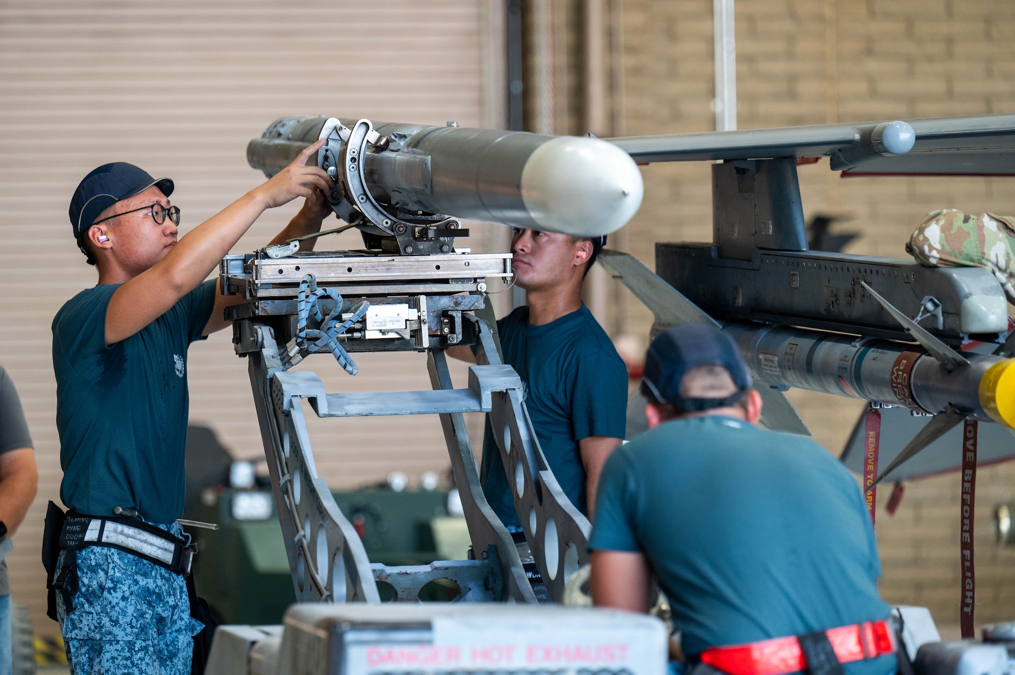 Republic of Singapore air force ME1 Wei Shen Tang (left), ME2 Yong Hao Wong (center), and ME2 Jeff Hong (right), load an AIM-120 AMRAAM missile onto an F-16 Fighting Falcon during the 56th Maintenance Group 2nd quarter weapons load competition, July 12, 2024, at Luke Air Force Base, Arizona.