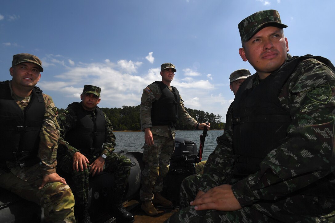 Maj. Jhon Chaparro, right, and Lt. Col. Jorge Flechas, second from left, both with the Colombian army’s engineer command, watch from a Combat Assault Craft as Soldiers with the 125th Multi-role Bridge Company, South Carolina Army National Guard assemble a raft on the Savannah River to move troops, vehicles, and equipment across the river as part of a training mission at Clarks Hill Training Site, S.C., July 17, 2024. The Colombian soldiers were observing the training as part of an exchange through the Department of Defense National Guard State Partnership Program.