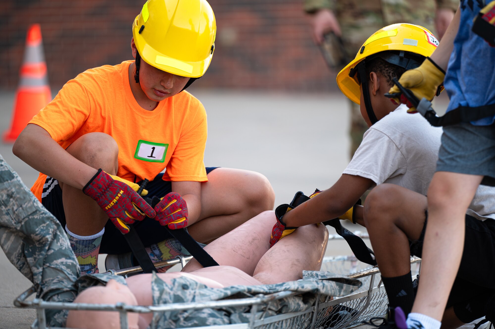 Children apply a tourniquet during Junior Firefighter Camp at Dyess Air Force Base, Texas, July 18, 2024. Dyess firefighters organized a drill for camp participants that included treating a victim and moving them to safety. (U.S. Air Force photo by Airman 1st Class Jade M. Caldwell)